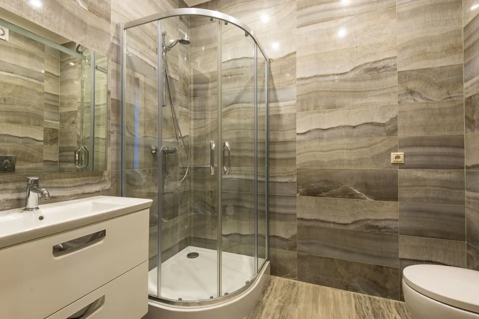 Cabine de douche d'angle posée sur un receveur à rebord