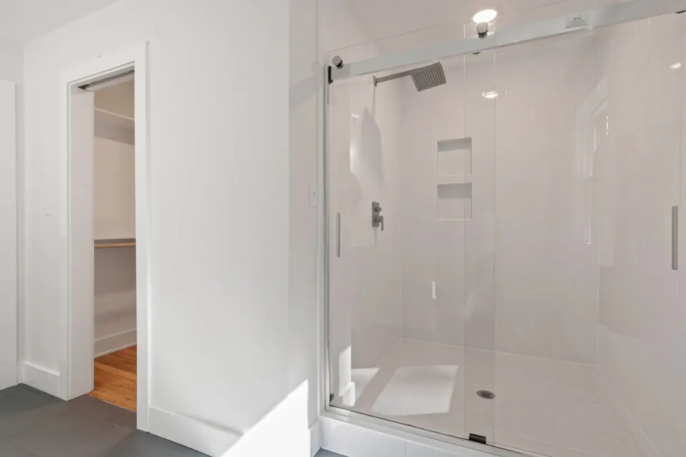Douche fermée par une porte vitrée coulissante sur un receveur bas