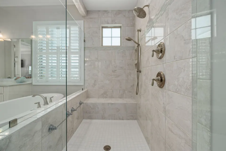 Grande douche de plain-pied carrelée, avec banc et douchette sur barre coulissante