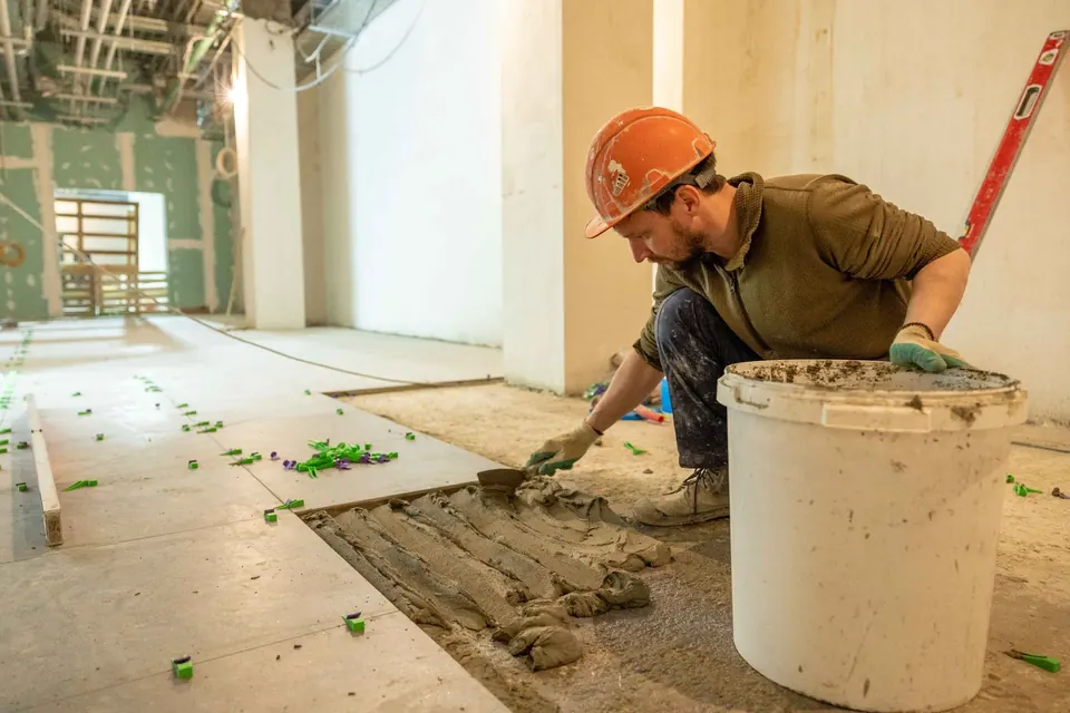 Professionnel préparant la pose d'un carrelage au sol pendant des travaux